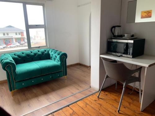 a green couch in a room with a desk and a television at Beach View B&B in East London