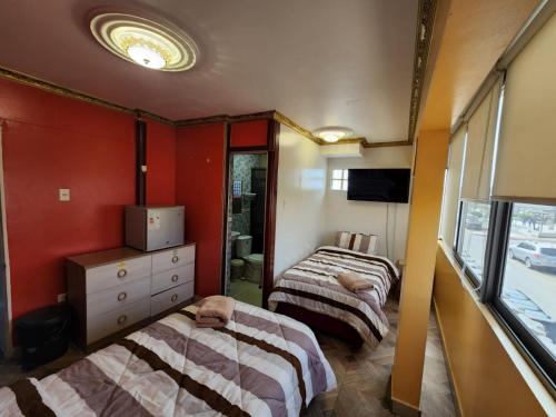 two beds in a room with red walls at Hotel La Pampa in Alto Hospicio