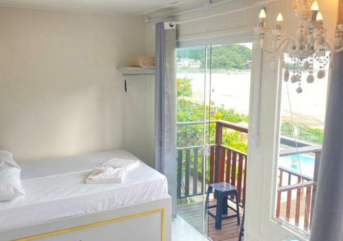 a room with a bed and a balcony with a view at Pousada São Miguel Beach Beira Mar in Penha