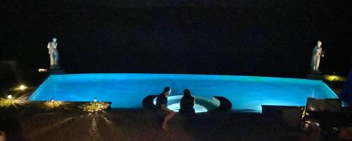 two people sitting in front of a blue pool at night at Magnificent Hudson River Estate in Coxsackie
