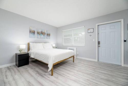 a white bedroom with a bed and a door at Just Off Wilton Drive Apt 5 in Fort Lauderdale