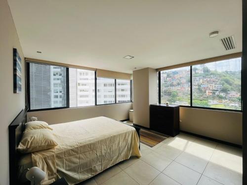 een slaapkamer met een groot bed en grote ramen bij SUITE TORRES BELLINI, PUERTO SANTA ANA in Guayaquil