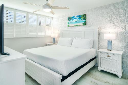 a white bedroom with a white bed and white windows at Kanai a Nalu 314 - Newly Renovated, Oceanfront, AC in Wailuku