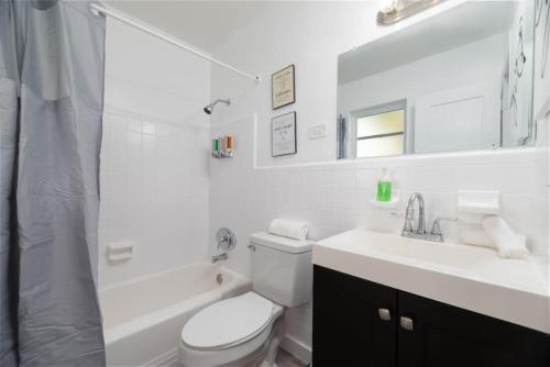 a white bathroom with a toilet and a sink at Just Off Wilton Drive Apt 6 in Fort Lauderdale