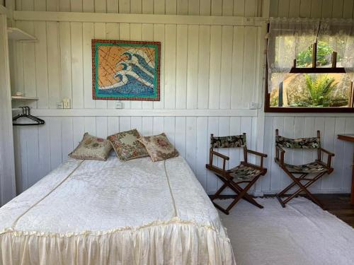 a bedroom with a bed and two chairs at Praia do Siriu in Siriú