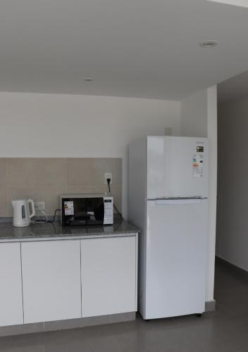 a kitchen with a white refrigerator and a microwave at Departamentos Ciudad de Nieva in San Salvador de Jujuy