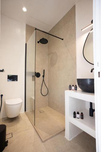 a bathroom with a glass shower with a toilet at Loom Suite Ornos in Mýkonos City