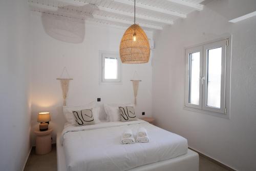 a white bedroom with a bed with shoes on it at Loom Suite Ornos in Mikonos