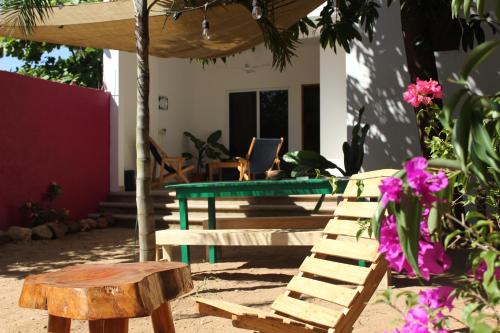 a patio with a table and a bench and flowers at Mi Puerto Beach Hostel in Puerto Escondido