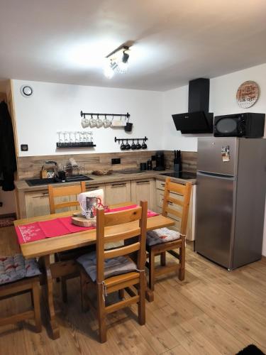 a kitchen with a wooden table with chairs and a refrigerator at La sapinette in La Bâthie