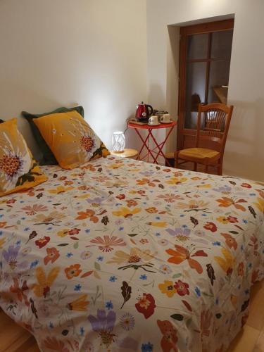 uma cama com um edredão floral num quarto em Chez Danièle et Jean-Pierre em Saint-Julien