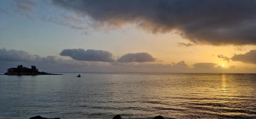 a sunset over the ocean with a small island in the water at La Casa sulla Spiaggia in Marzamemi