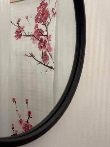 un espejo con un reflejo de una rama con flores rojas en H-36 RESIDENCE 0.1 en Koblenz