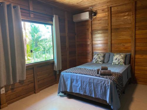 a bedroom with a bed and a large window at Cabana das Mandalas in Itacaré