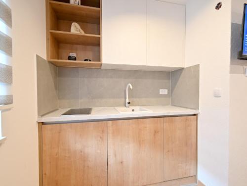Una cocina con fregadero y armarios de madera. en Grand Apartman Jahorina, en Jahorina