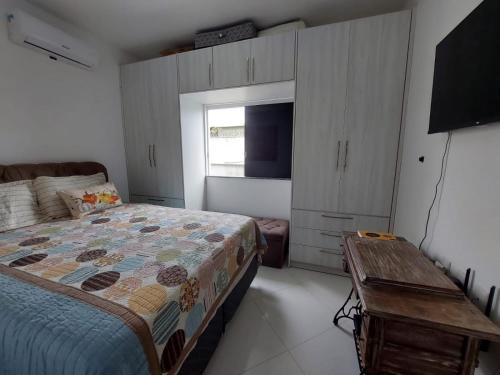 1 dormitorio con 1 cama, TV y mesa en apartamento vizinho ao mar, en Porto Seguro