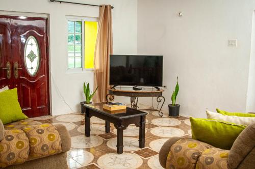 uma sala de estar com uma televisão e uma mesa em Veronica Homestay Lucea Jamaica em Lucea