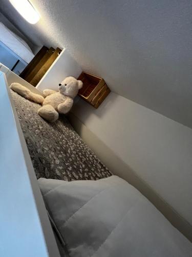 a stuffed teddy bear sitting on a bed in a room at La joue du loup, aux pieds des pistes et vue sur montagnes in La Joue du Loup