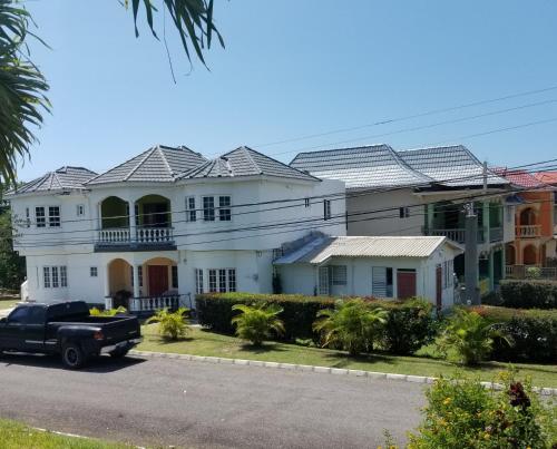 a truck parked in front of a large white house at Veronica Homestay Lucea Jamaica in Lucea
