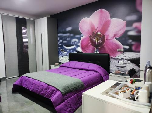 um quarto com uma cama roxa e uma flor na parede em B&B La Grotta em Nicolosi