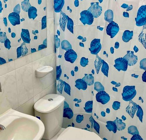 a bathroom with a toilet and a blue and white shower curtain at Casa Luna Llena in Cali