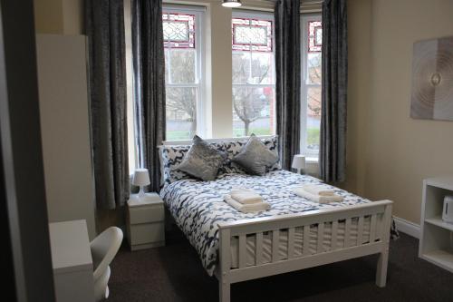 1 dormitorio con cama con almohadas y ventanas en Station Rooms, en Londonderry County Borough