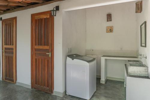 a laundry room with a washing machine and a wooden door at Glamping Coco Dendê - Algodões in Praia dos Algodões