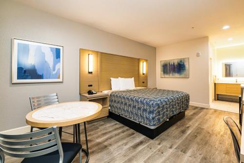 a hotel room with a bed and a table and chairs at Palace Inn Blue-IAH East in Humble