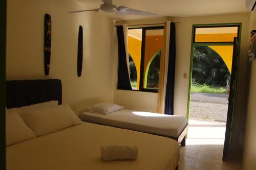 a bedroom with two beds and a window and a door at Cool & Calm Hotel in Manzanillo