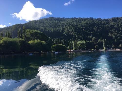 a boat on a river with mountains in the background at Casa en Choshuenco a 180 metros de la Playa, Panguipulli, Los Ríos in Panguipulli
