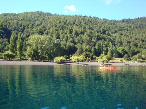 a couple of people in a red boat on a lake at Casa en Choshuenco a 180 metros de la Playa, Panguipulli, Los Ríos in Panguipulli