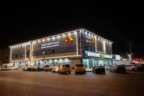 un edificio con auto parcheggiate di fronte di notte di تارا واحد للشقق المخدومة a Riyad
