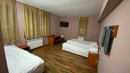 a hotel room with two beds and a television at Хотел Враца in Vratsa