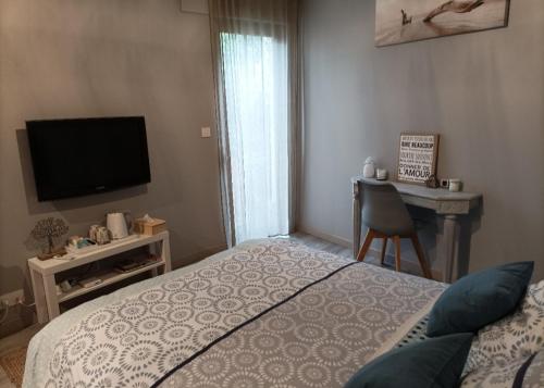 een slaapkamer met een bed, een televisie en een bureau bij Cocon au pied de la Chartreuse in Lumbin