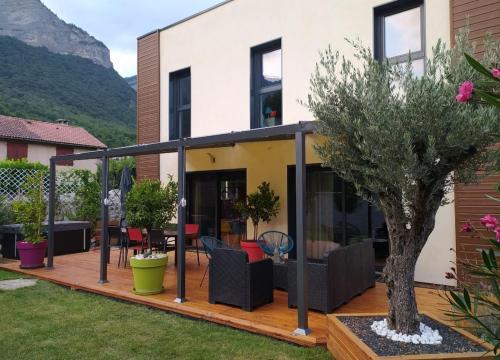 una terraza al aire libre con muebles y un árbol en Cocon au pied de la Chartreuse, en Lumbin