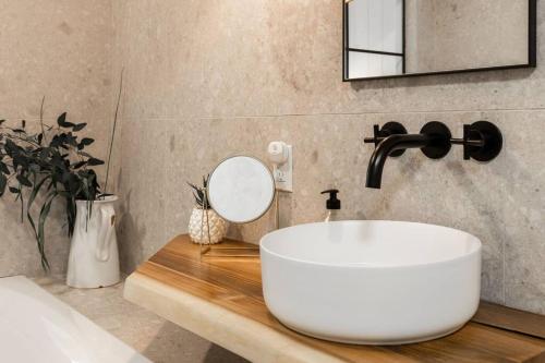 a bathroom with a white sink and a mirror at Luxurious & Modern Tremblant Loft Pool&Spa Access in Mont-Tremblant
