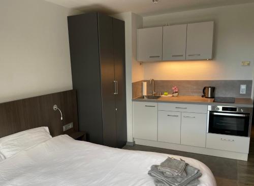 a bedroom with a bed and a kitchen with white cabinets at Hafen Pano Lux Appartment +Küche+TV+AC+TG+View in Düsseldorf