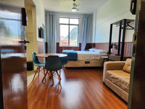 Habitación de hotel con cama, mesa y sillas en Flat 335 - excelente localizacão, estacionamento, en Teresópolis