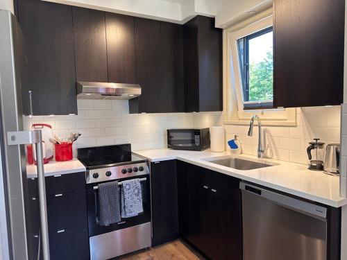 a kitchen with black cabinets and a stove and a sink at Vineyard Suite at The Inn On The Drive in Vancouver
