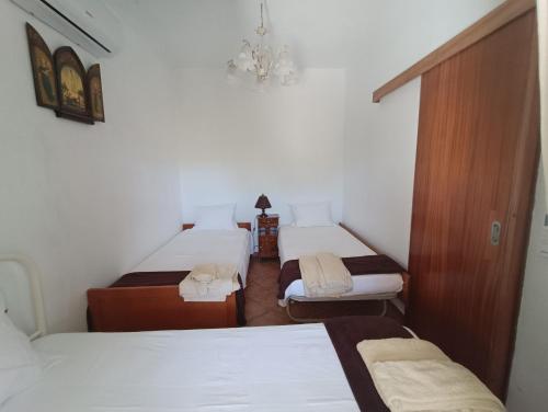 a room with three beds and a chandelier at Casa dos Avós in São Brás de Alportel