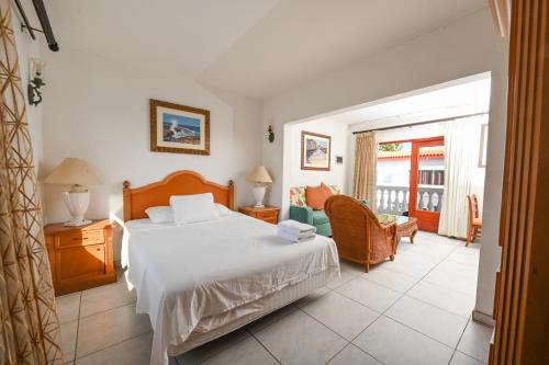 a bedroom with a bed and a chair and a window at E Solo Aruba Apartments in Oranjestad