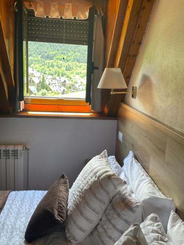 a bedroom with a bed and a window with a view at Hostal Escuils in Unha