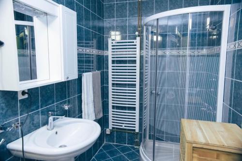 uma casa de banho em azulejos azuis com um lavatório e um chuveiro em Hills em Travnik