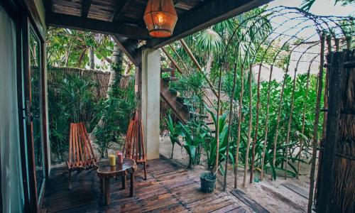 weranda ze stołem, krzesłami i roślinami w obiekcie Orchid House Tulum Beach w mieście Tulum