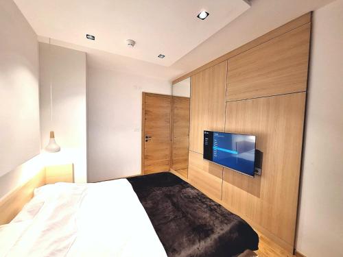 a bedroom with a bed and a flat screen tv at Apartman Vuk, Apart hotel Zlatni javor in Jahorina