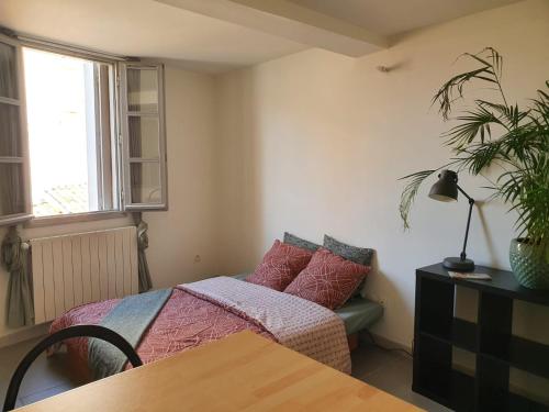 a bedroom with a bed and a table and a window at Studio au coeur de Montpellier in Montpellier