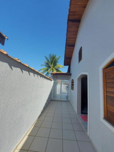 a hallway of a white building with a palm tree at CASA DE PRAIA MARAVILHOSA PERUIBE in Peruíbe