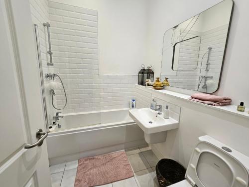 a white bathroom with a sink and a bath tub at Characteristic loft style apartment in Birmingham