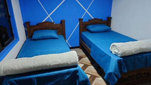 2 Betten in einem Zimmer mit blauen Wänden in der Unterkunft Hospedaje Villa Salome in Pereira