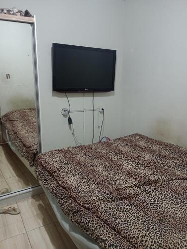 1 dormitorio con 1 cama y TV de pantalla plana en la pared en Casa Penha, en Río de Janeiro